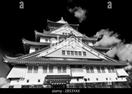 Kontrastierende schwarz-weiße Fassade des spektakulären historischen Burgturms in der japanischen Stadt Osaka gegen den klaren Himmel. Stockfoto