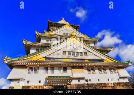 Hell beleuchtete Fassade des spektakulären historischen Burgturms in Osaka, der Stadt Japan, gegen den blauen Himmel. Stockfoto