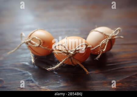 Osterbeige Eier schmücken mit Seil auf braunem Holzhintergrund mit Copyspace Stockfoto