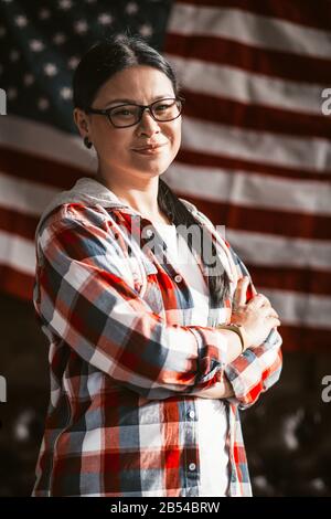 Patriotische Frau, Die Stolz Auf Amerikas Flag Background Posiert Stockfoto