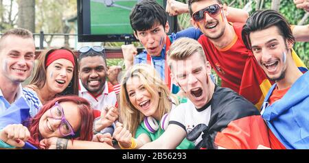 Fröhliche Sportfans, die während des Fußballweltspiels Spaß haben - Junge Anhänger im Pub beim Fußballspielen im Freien - Freundschaft, Sport, Kleben und Jugend Stockfoto