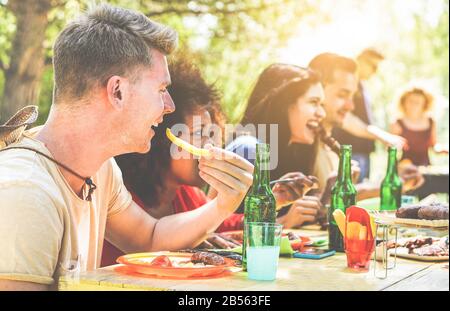 Fröhliche Freunde grillen am Sommertag im Garten im Hinterhof - Junge fröhliche Leute essen leckeres Fleisch bbq Dinner - Konzept über positive Stimmung Stockfoto