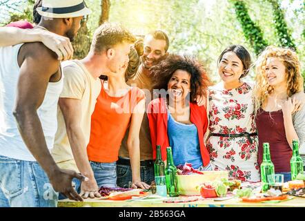 Eine Gruppe glücklicher Freunde, die auf der Grillparty im Freien im Hinterhof des Hauses Spaß haben - Junge, vielseitige Kulturschaffende, die bbq-Abendessen machen - Jugend, Essen und Frien Stockfoto