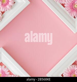 Flacher Lay aus weißen Rahmen mit rosa Blumen gerberas auf pastellrosa Hintergrund, Kopierraum. Fröhlicher Muttertag, Frauentag, Valentinstag oder Birthda Stockfoto