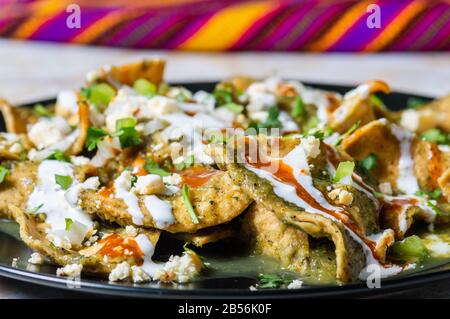 Green Chilaquiles, traditionelles mexikanisches vegetarisches Frühstück aus gebratenen Tortillas und mit grüner Sauce Stockfoto