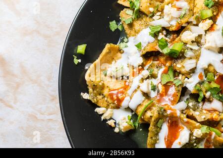 Green Chilaquiles, traditionelles mexikanisches vegetarisches Frühstück aus gebratenen Tortillas und mit grüner Sauce Stockfoto