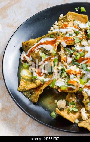 Green Chilaquiles, traditionelles mexikanisches vegetarisches Frühstück aus gebratenen Tortillas und mit grüner Sauce Stockfoto