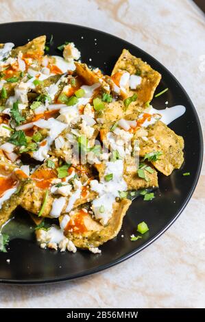 Green Chilaquiles, traditionelles mexikanisches vegetarisches Frühstück aus gebratenen Tortillas und mit grüner Sauce Stockfoto