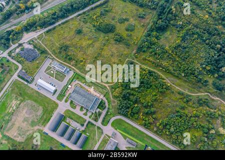 Drohnenbild des Industriegebietes in den Vorstädten der Stadt: Herstellung von Firmen und Lagerhäusern in der Nähe von Wald Stockfoto