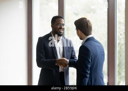 Überfreudige multirassische Geschäftspartner schütteln nach dem Treffen die Hände Stockfoto