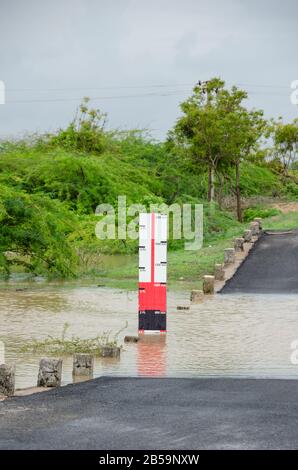 Der Wasserspiegel am Straßenrand zeigt die Wassertiefe des Hochwassers bei starken Regenfällen in Mandvi, Kutch, Gujarat, Indien Stockfoto