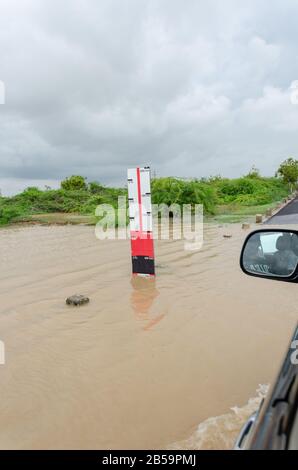 Der Wasserspiegel am Straßenrand zeigt die Wassertiefe des Hochwassers bei starken Regenfällen in Mandvi, Kutch, Gujarat, Indien Stockfoto