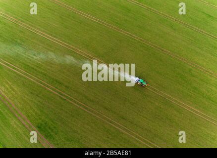 Gammelin, Deutschland. März 2020. Ein Traktor fährt über ein Feld und verteilt Pflanzendünger mit einem Hebegerät (Luftbild mit Drohne). Die Umweltschutzorganisation Bund hat die Landesregierung Mecklenburg-Vorpommern aufgefordert, das Landesprogramm Bodenschutz umzusetzen. Ziel ist es, den guten Zustand des Bodens auf den Feldern, Wiesen und Weiden zu erhalten oder wiederherzustellen. Kredit: Jens Büttner / dpa-Zentralbild / dpa / Alamy Live News Stockfoto