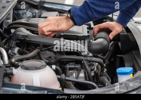 Nahaufnahme des mechanischen Handprüfmotors unter der Haube im zerbrochenen Auto. Reparatur des Fahrzeugkonzepts. Automobilservice Stockfoto