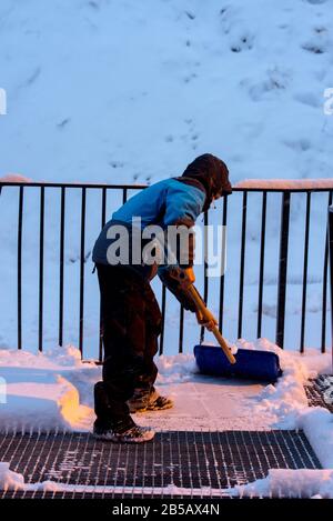 Der Mensch entfernt an einem Wintertag in Andorra Schnee mit einer Schaufel. Stockfoto