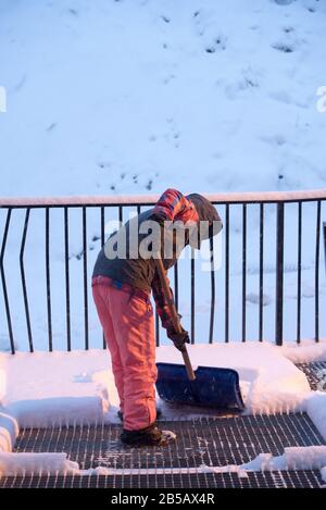 Frau entfernt an einem Wintertag in Andorra Schnee mit einer Schaufel. Stockfoto