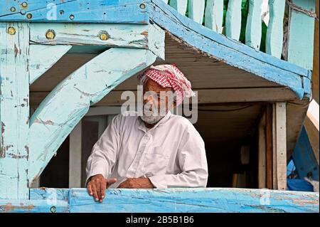 Dubai, vae - 2020.02.22: Der Kapitän einer arabischen Holzdhow auf seinem Schiff während des Berthingmanövers am dubai deira Creek dhow wharfage Stockfoto