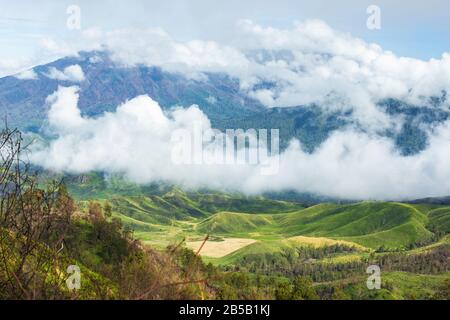 Atemberaubende Aussicht auf die schöne Bergwelt von Wolken bei Sonnenaufgang umgeben. Ijen Vulkans komplex. Stockfoto