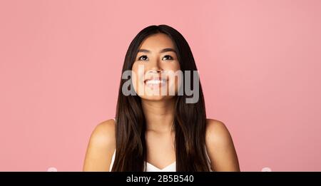 Asian Girl Smiling Looking Up Over Pink Studio Background, Panorama Stockfoto