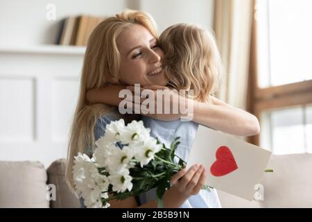 Kleines fürsorgliches Mädchen grüßt Mutter mit Geburtstag Stockfoto