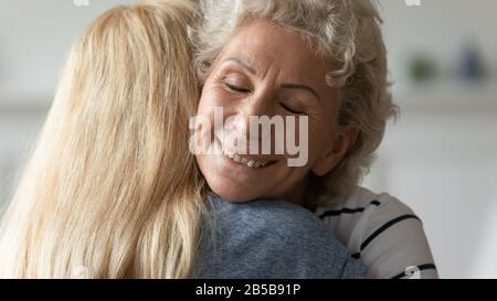 Die fröhliche Umarmung der Mutter umarmt die Erwachsene Tochter Stockfoto