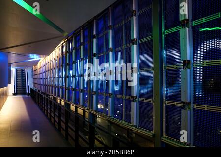 LED-Musteranlage an der Spiegelglaswand von innen nach außen mit Rolltreppe. Stockfoto