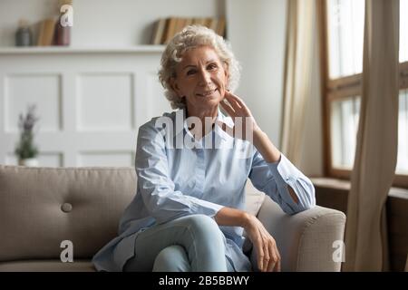 Porträt einer lächelnden Seniorin entspannen Sie sich auf der Couch Stockfoto