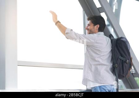 Nach Der Ankunft. Glücklicher Mann Winkt Hand Vom Fenster Im Flughafenterminal Stockfoto