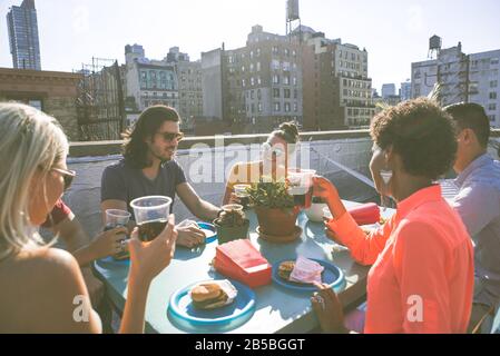 Eine Gruppe von Freunden, die auf einem Dach in New york zusammen Zeit verbringen, ein Lifestyle-Konzept mit glücklichen Menschen Stockfoto