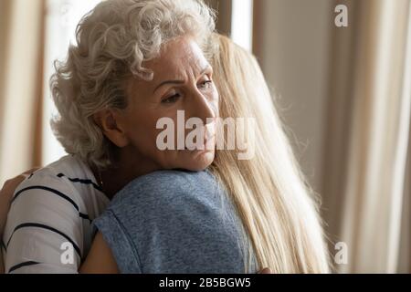 Traurige, reife Mutter und Erwachsene Tochter umarmen sich und zeigen Unterstützung Stockfoto