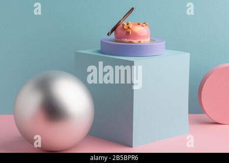 Bunte 3D-Formen und rosafarbener Mousskuchen auf blauem Hintergrund Stockfoto