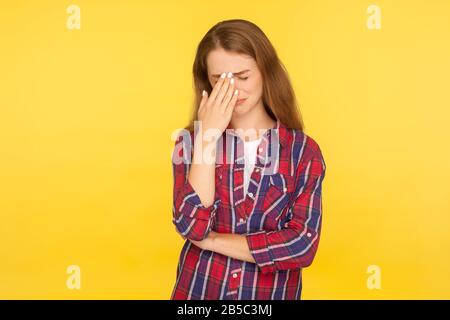 Trauer und Depressionen. Porträt eines dramatischen weinenden Ingwermädchens im karierten Hemd, das Tränen wegwischt, sich verzweifelt hilflos fühlt, sich Sorgen um das Problem macht. Stockfoto