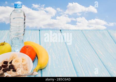 Gesundes Frühstück. Haferbrei mit Rosinen in einer weißen Schüssel, grüner Apfel, Bananen. Flache Draufsicht. Kopierbereich Stockfoto
