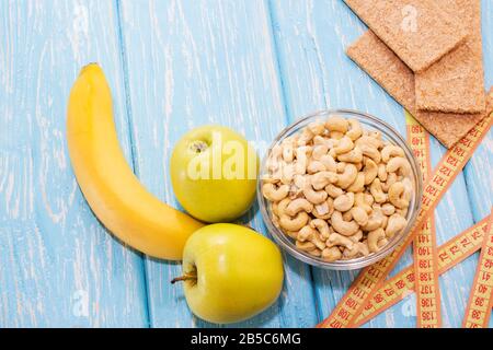 Gesundes Frühstück. Cashew Nüsse in einer weißen Schüssel. Grüner Apfel, Banane. Humor. Männliche Potenz Stockfoto