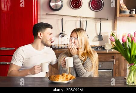 Süße Freundin und Freundin mit Kaffee und Croissants zum Frühstück in der Küche Stockfoto