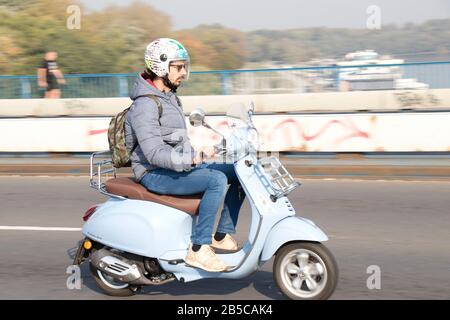 Belgrad, Serbien - 17. Oktober 2019: Ein junger Mann, der mit einem hellblauen vespa-motorroller auf der Stadtbrücke unterwegs ist, wird geschwenkt Stockfoto