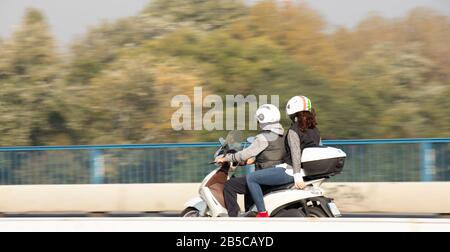 Belgrad, Serbien - 17. Oktober 2019: EIN Paar, das auf einem vespa-roller auf der Autobahnbrücke fährt und von hinten schwenkt Stockfoto