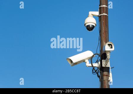 Zwei Sicherheitskameras an einem Pfosten gegen einen blauen Himmel Stockfoto