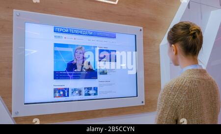 Frau Fernsehen Nachrichten auf interaktive Display Wall Stockfoto