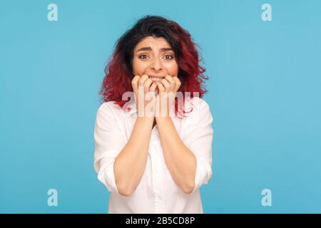 Porträt einer ängstlichen Panierin mit ausgefallenen roten Haaren, die Nägel beißt und mit ängstigendem Ausdruck aussieht, nervös wegen Problemen, Problemen. Stockfoto