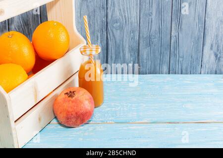 Viel Orangen im Karton und eine Flasche Saft, roter Granatapfel, Kokosnuss. Gesunde Ernährung. Stockfoto