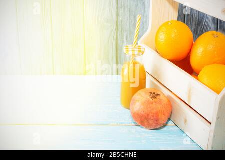 Viel Orangen im Karton und eine Flasche Saft, roter Granatapfel, Kokosnuss. Gesunde Ernährung. Stockfoto