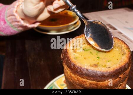 Eine Frau isst hausgemachte Suppe von einem Teller Brot. Stockfoto