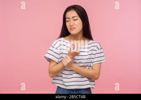 Handgelenk verstauchung. Portrait des Mädchens mit brünettem Haar, das verletzte Hand berührt, die in den Schmerz grimacing, leidende Karpaltunnelsyndrome, Arthritisentzündung. I Stockfoto