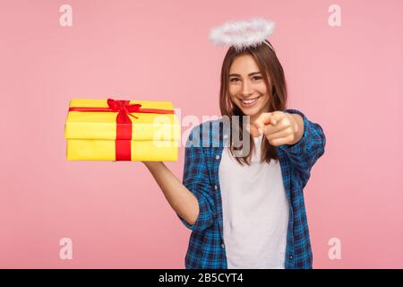 Geschenk von Angel für Sie! Portrait eines großzügigen, schönen Mädchens mit einem Kopf über dem Kopf, der auf die Kamera zeigt und das Geschenk hält. Ich gratuliere zum Geburtstag Stockfoto