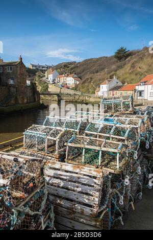 Staithes, North Yorkshire, Großbritannien, eine traditionelle Hafenszene in Fischerdörfen mit Fischtöpfen im Vordergrund. Stockfoto