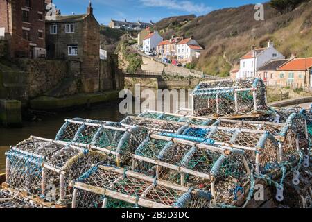 Staithes, North Yorkshire, Großbritannien, eine traditionelle Hafenszene in Fischerdörfen mit Fischtöpfen im Vordergrund. Stockfoto