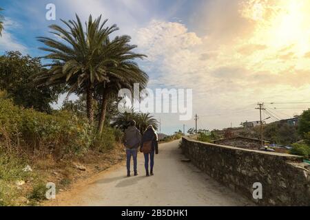 Ein Paar Unternehmen bei Sonnenaufgang einen Spaziergang entlang einer Bergstraße am Berg Abu Rajasthan. Mount Abu ist eine Hügelstation im westindischen Bundesstaat Rajasthan Stockfoto
