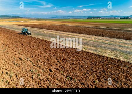 Luftdrohne schoss von einem Bauern in Traktorseeding und säte landwirtschaftliche Nutzpflanzen auf dem Feld auf den fruchtbaren Bauernfeldern von Kilkis in Nordgriechenland Stockfoto