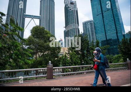 Kuala Lumpur, Malaysia. März 2020. Zwei Frauen, die Masken tragen, gehen im KLCC-Park in Kuala Lumpur, Malaysia, 8. März 2020. Sechs neue Fälle von COVID-19 wurden am Sonntag in Malaysia gemeldet, was die Gesamtzahl der Fälle auf 99 brachte, sagte das Gesundheitsministerium. Credit: Zhu Wei/Xinhua/Alamy Live News Stockfoto